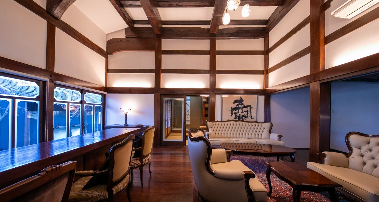 Lounge with antique upholstered sofas and exposed timber-beamed ceiling at the Yufuin inn