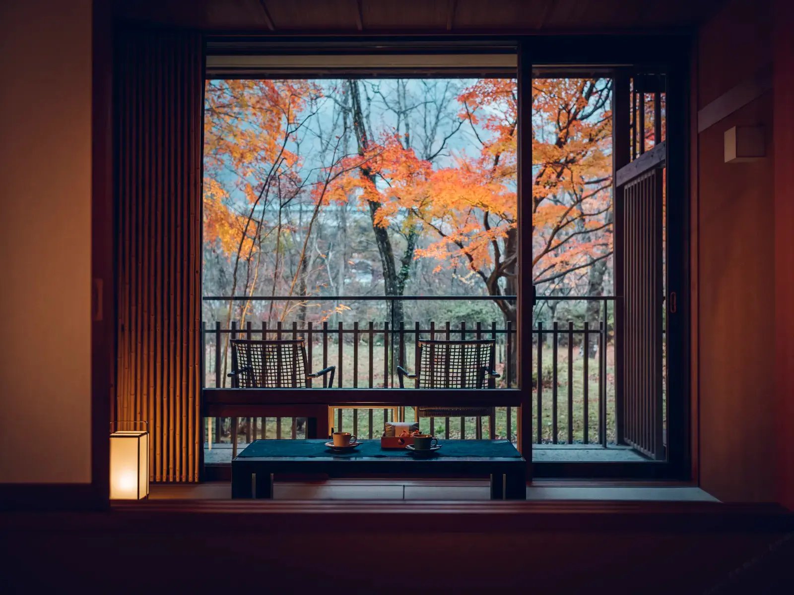 Guest room framing a terrace and autumn trees through wide windows
