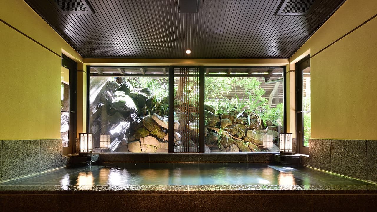 Indoor stone bath overlooking a lantern-lit rock garden