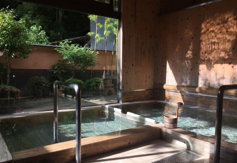 Indoor wooden hot spring bath with a garden view through large windows