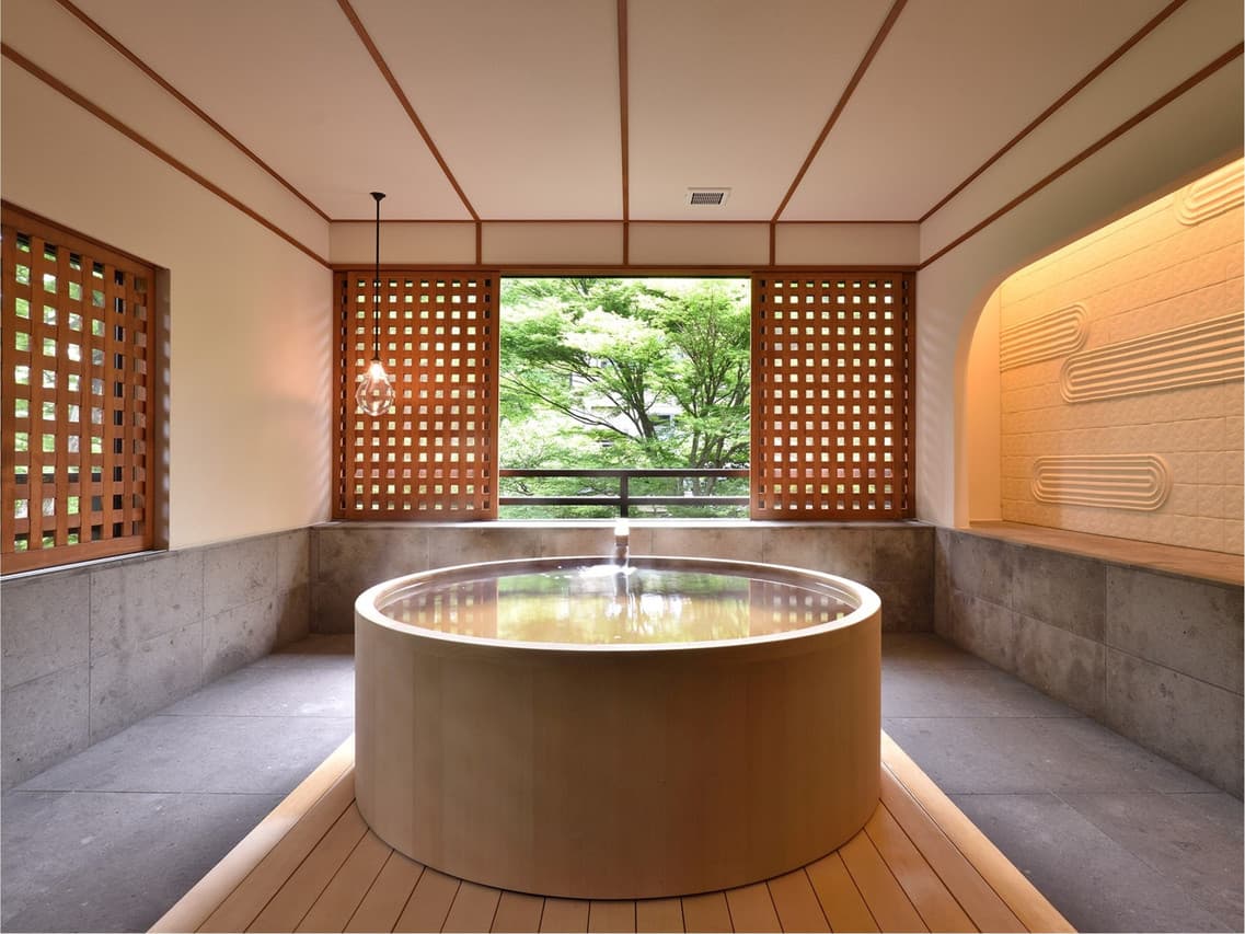 Round hinoki wood tub in a room with wooden lattice walls
