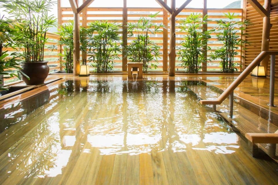 Sunlit indoor hot spring bath with bamboo and wood interior