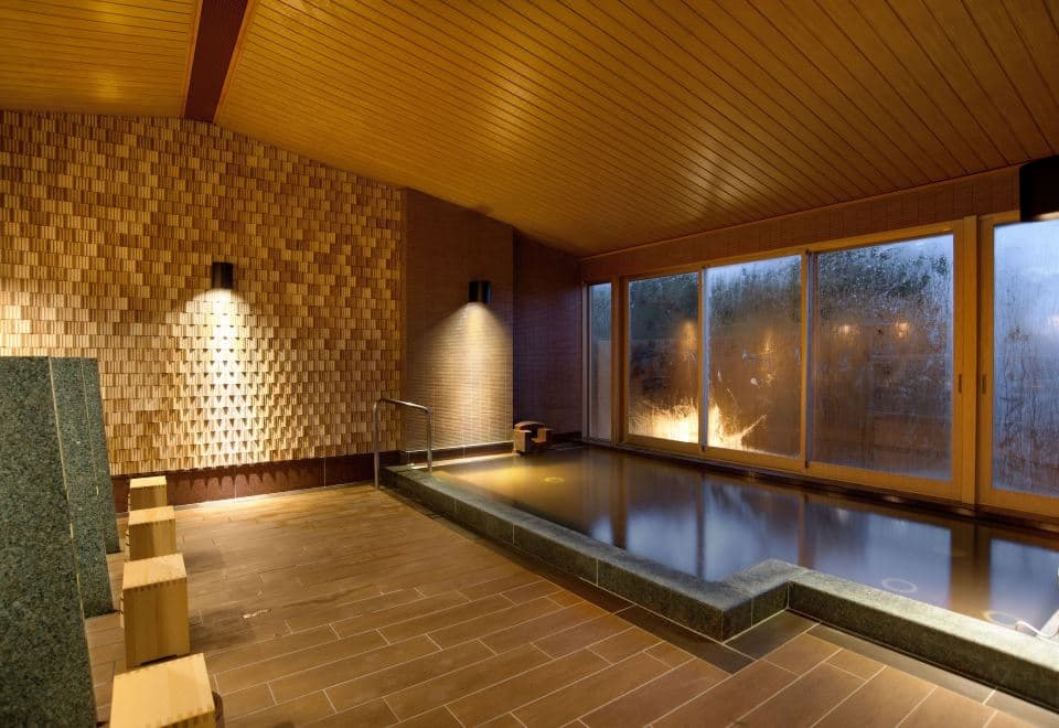 Atami Sekaie indoor onsen bath with textured wooden wall accent and wide garden window