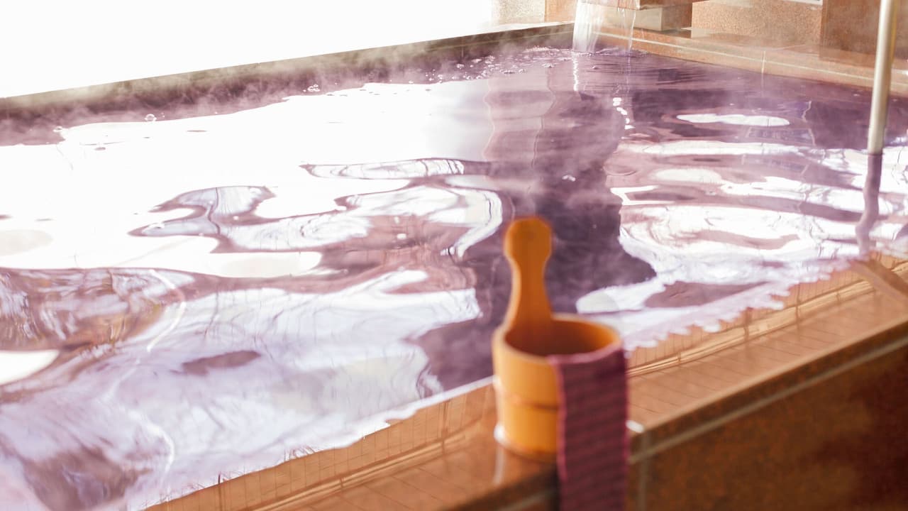 Steaming hot-spring bath with a wooden ladle at the edge