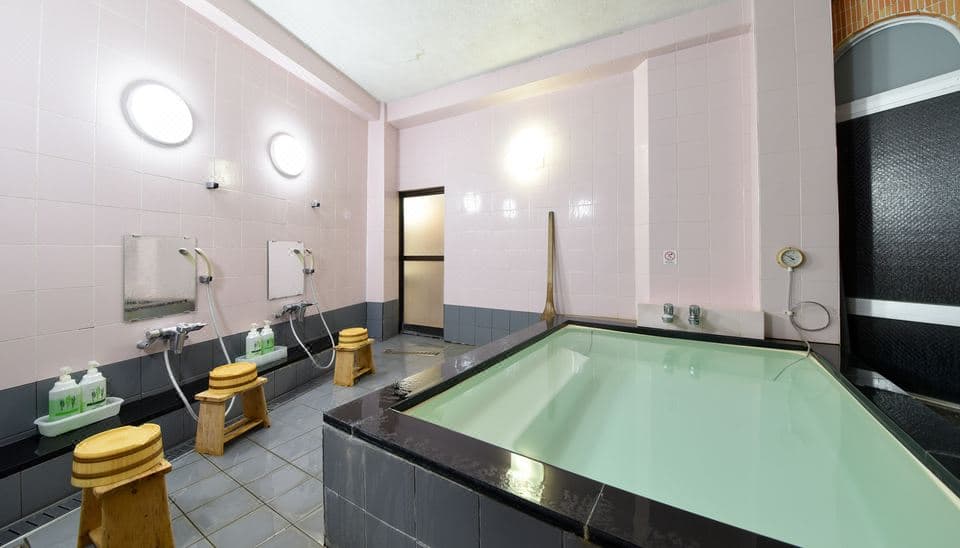Atami Shogetsu communal hot spring bath with pale-green mineral water and hinoki wash stools
