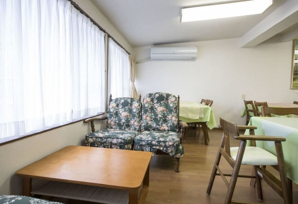 Atami Shogetsu common lounge area with floral armchairs and dining tables by garden windows