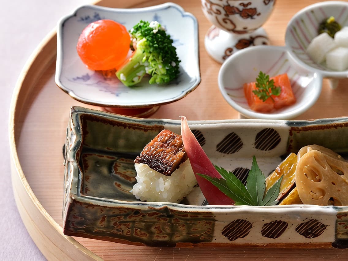 Kaiseki appetizer plated on ceramic dishes on a wooden tray