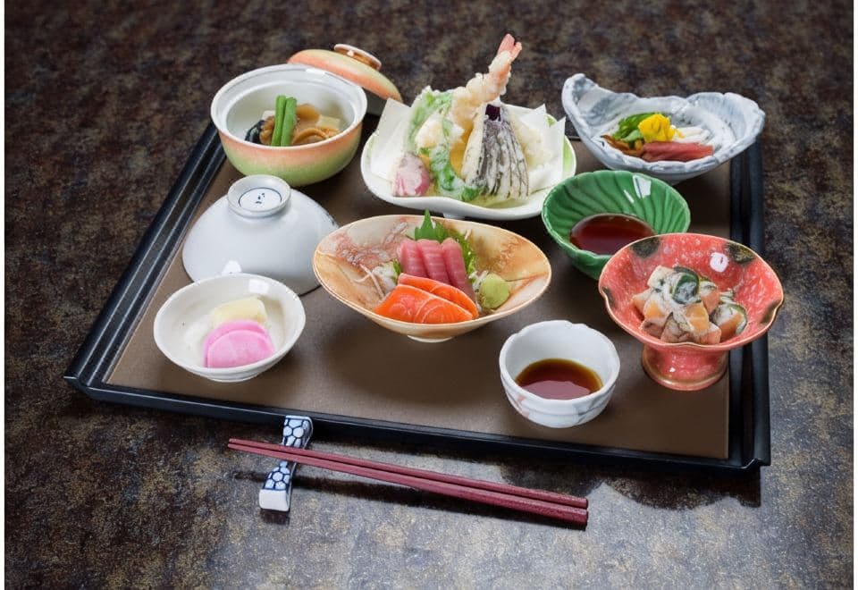 Multi-dish set meal with sashimi, tempura and small side dishes on a black tray