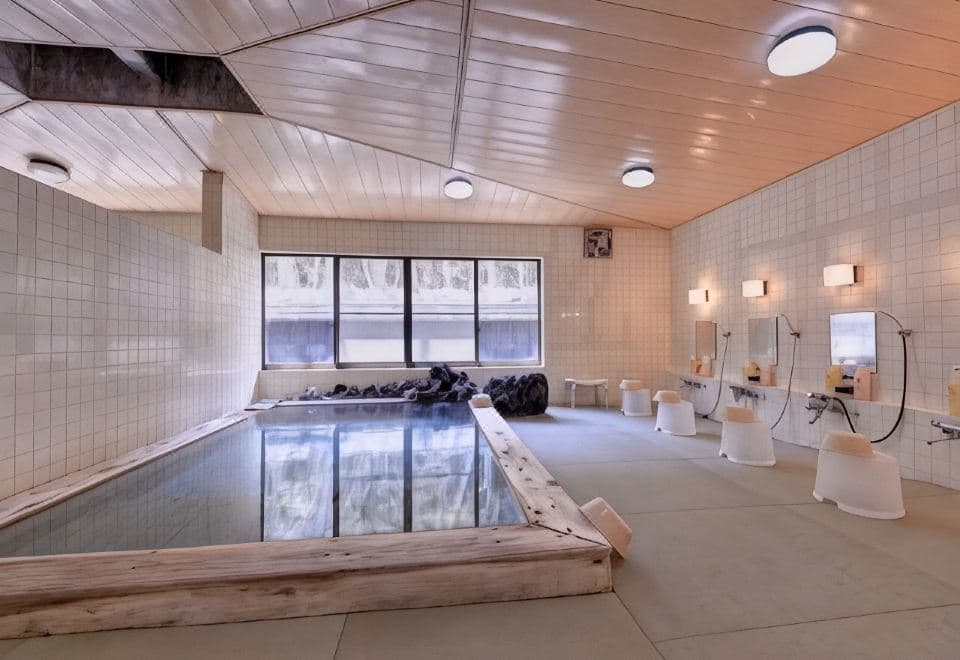 Large white-tiled indoor bath with a deep source-fed pool and washing stations