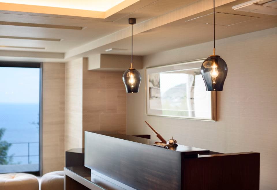 Atami Sekaie front reception desk with smoked-glass pendant lamps and ocean-view window