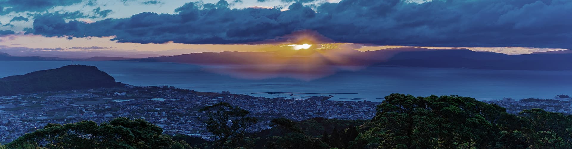 Bettei Amafuru Oka hilltop resort above Ibusuki at sunset, building set on a forested ridge over Kagoshima Bay