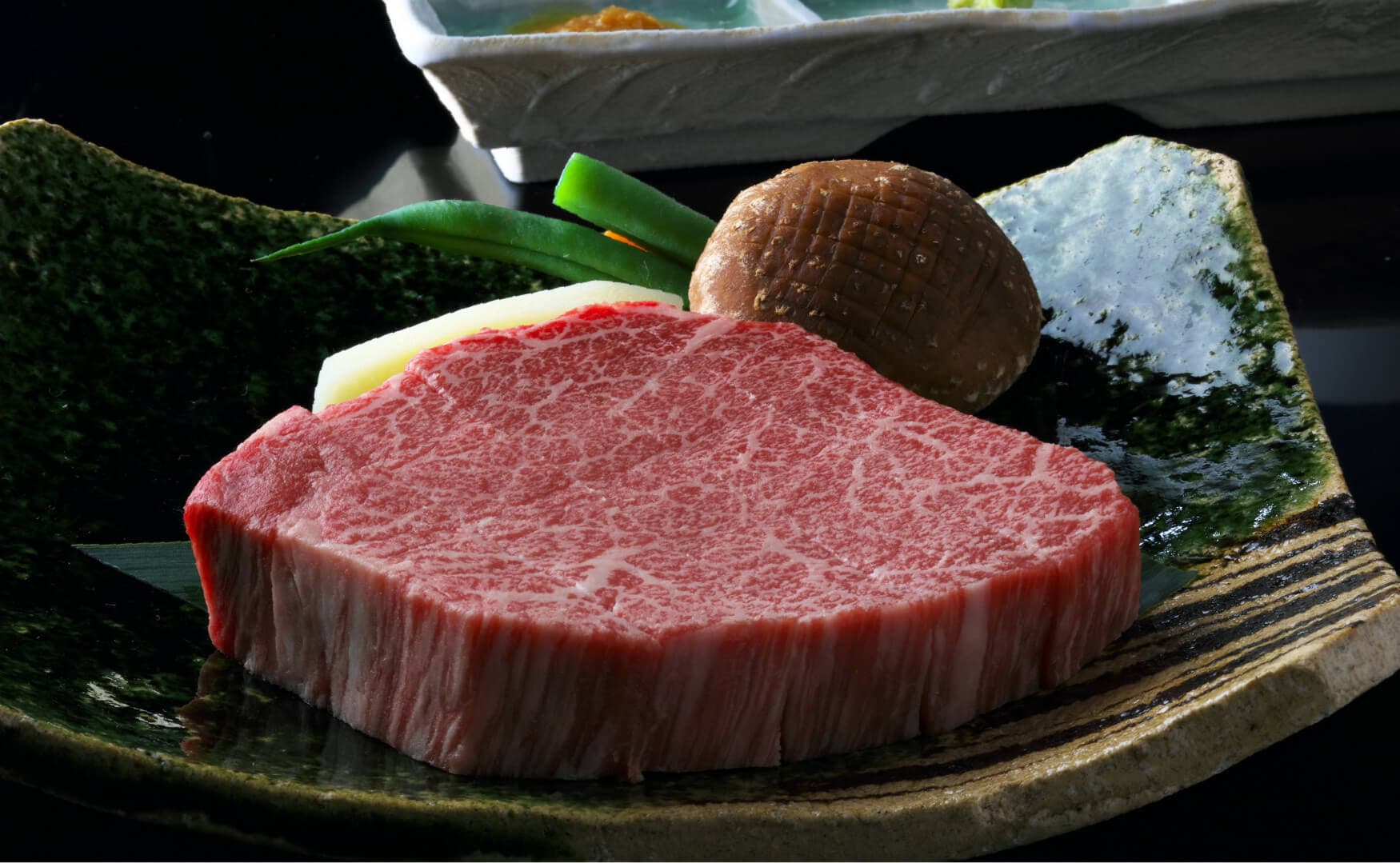 Minimalist plating of marbled Kobe beef and a small simmered course on ceramic dishes for a premium kaiseki dinner at Takayamaso Hanano, Arima Onsen