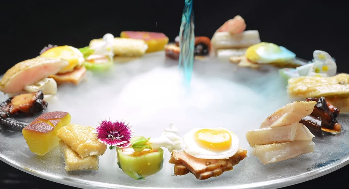 Artistic kaiseki appetizer platter at Oku no Hosomichi arranged in a ring on a silver plate with rising aromatic smoke