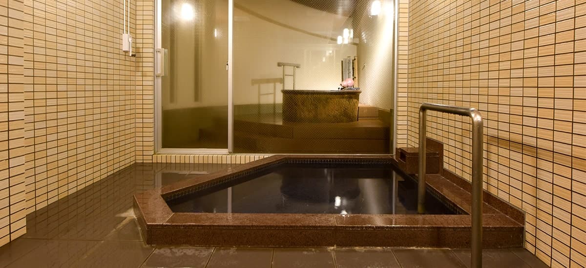 Private reservable bath at Oku no Hosomichi with clear ginsen water, beige tiled surround and garden-view window