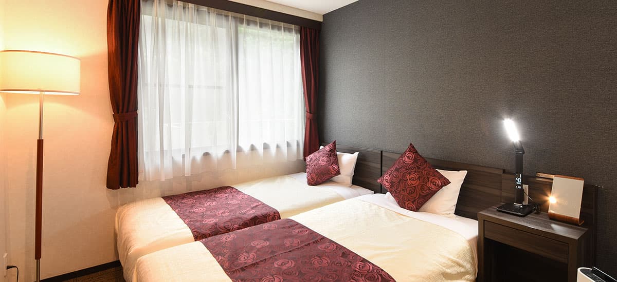 Koki Hollywood twin guest room with two beds pushed together beneath a sheer-curtained window
