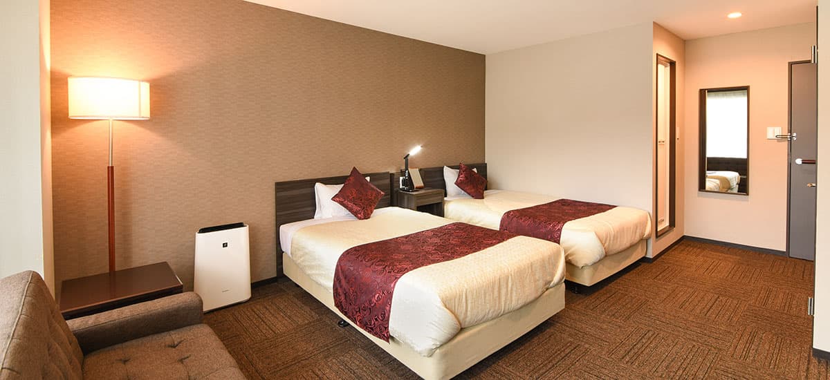 Koki semi-double twin guest room with warm lighting, twin beds and burgundy rose bed runners