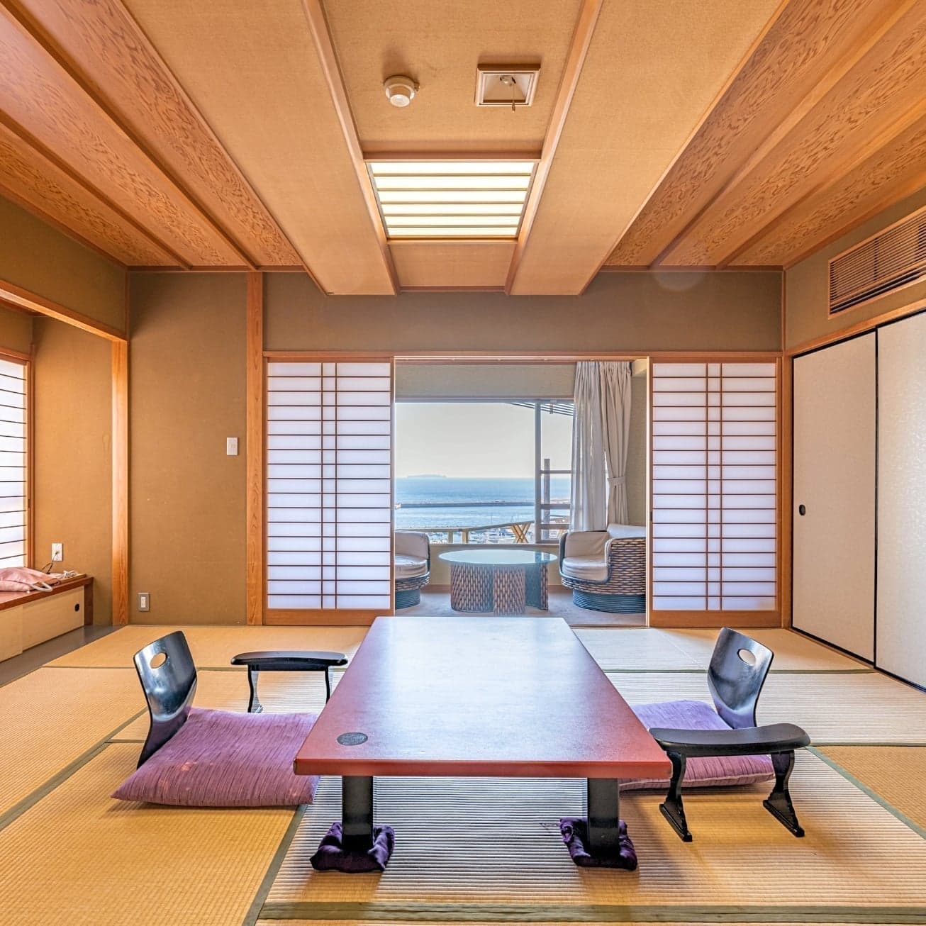 Spacious Japanese-style room with shoji screens and sea-view veranda at Hotel Kanichi