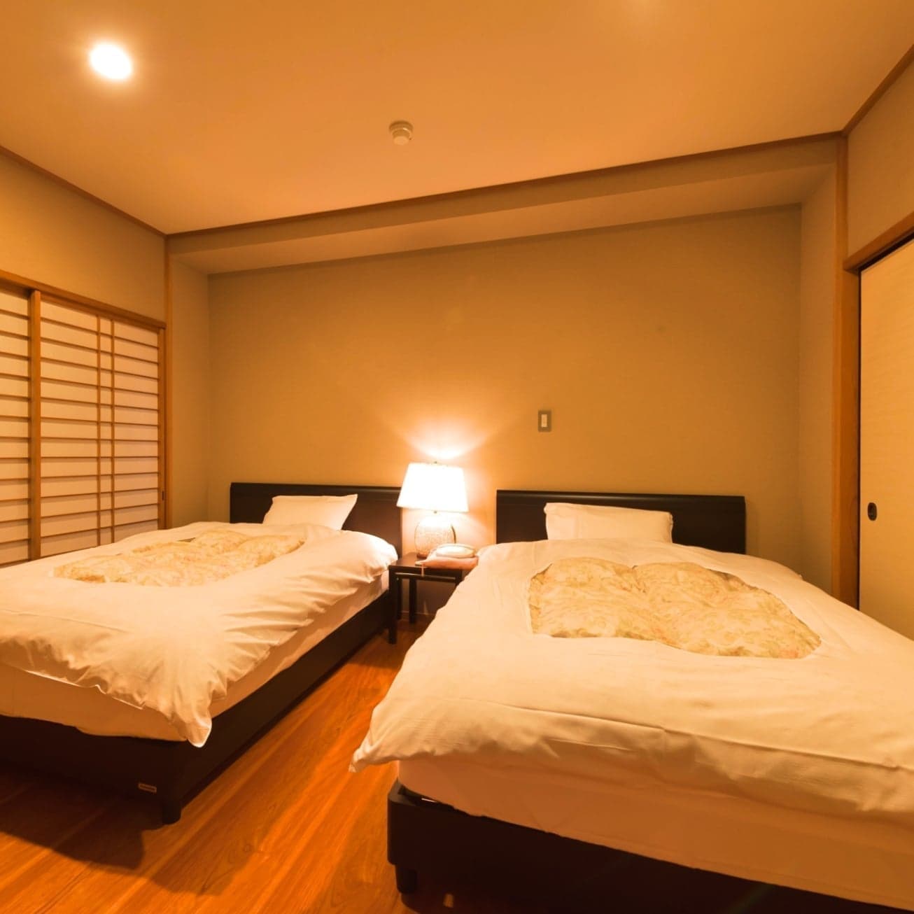 Warmly lit twin-bed Japanese-Western room with shoji screen at Hotel Kanichi