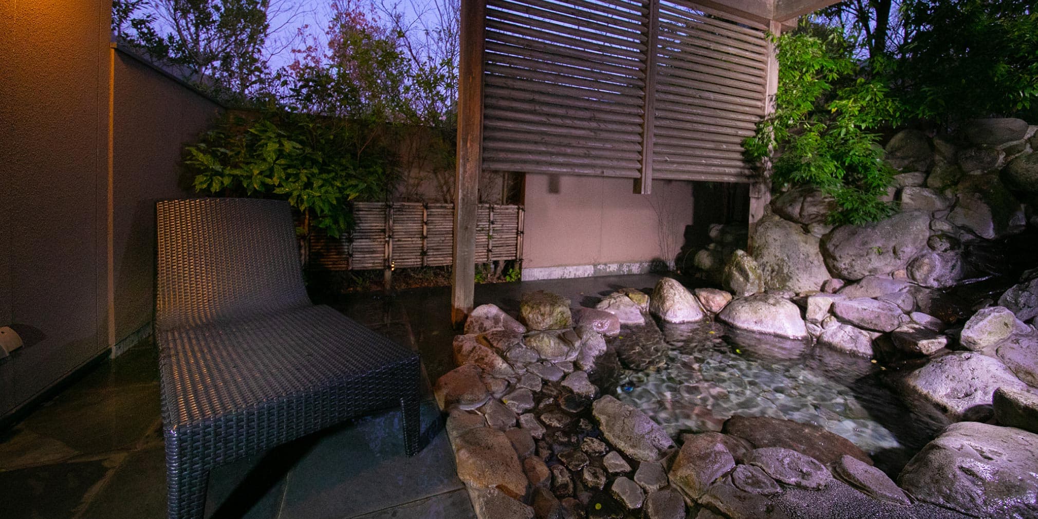 Private outdoor rotenburo bath with rock waterfall and lounge chair at dusk, Yufuin Bettei Itsuki