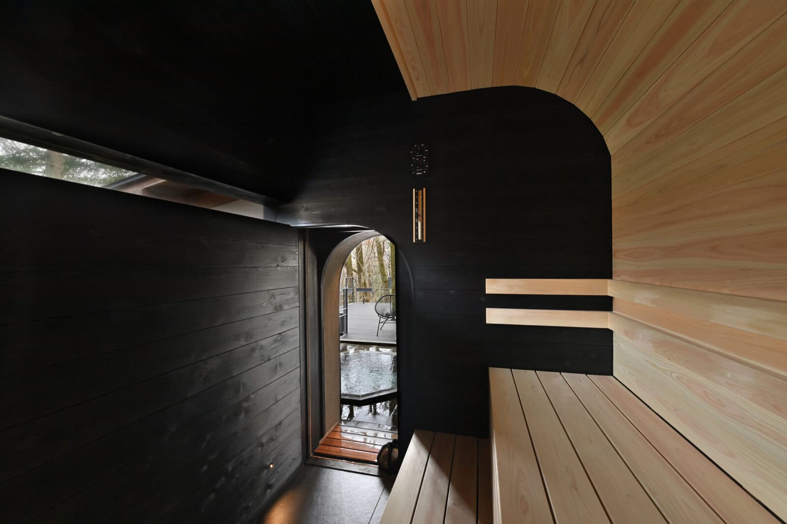 Hexagonal stone open-air bath with light rays through a forest canopy