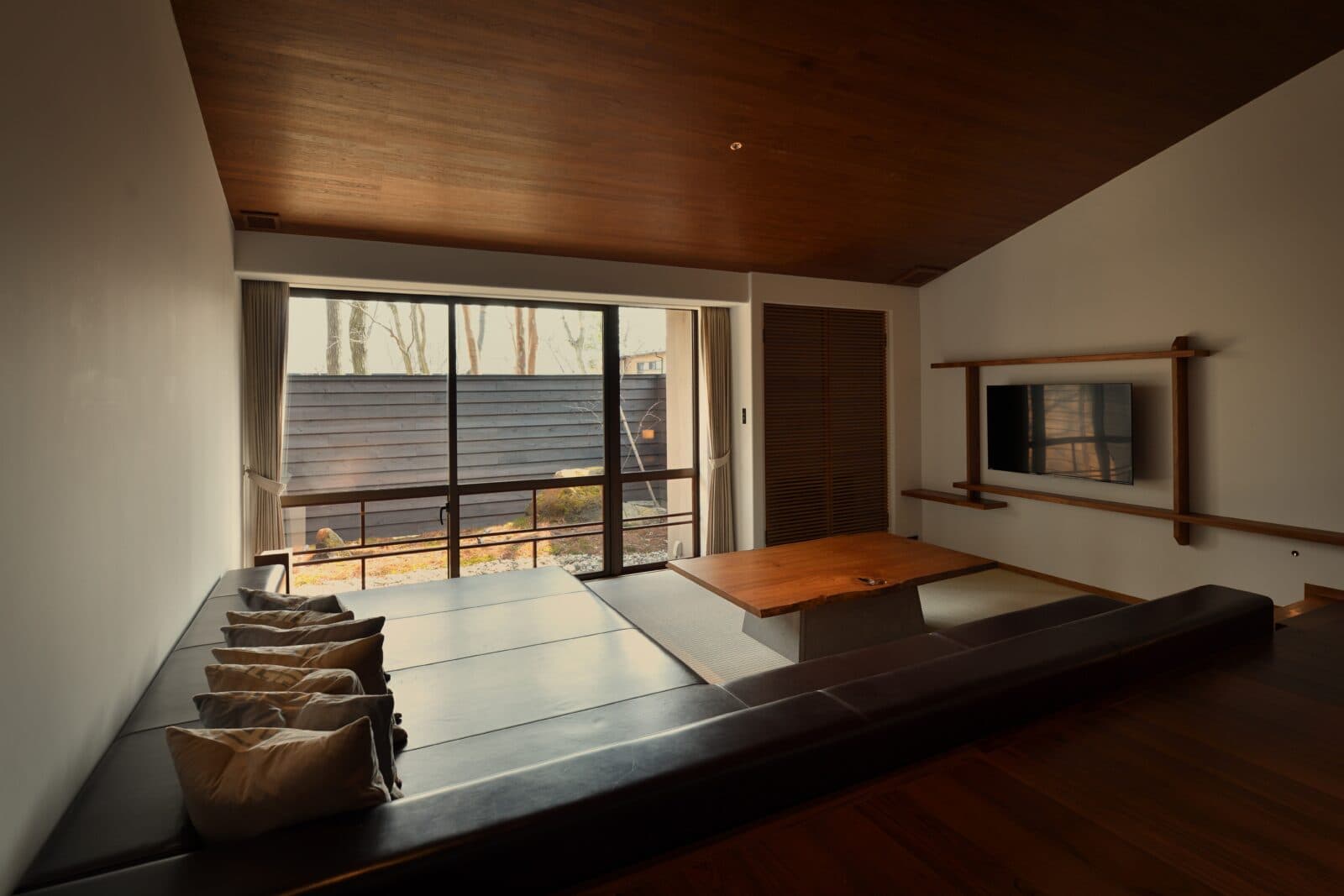 Suite living room with sunken sofa seating facing a forest garden