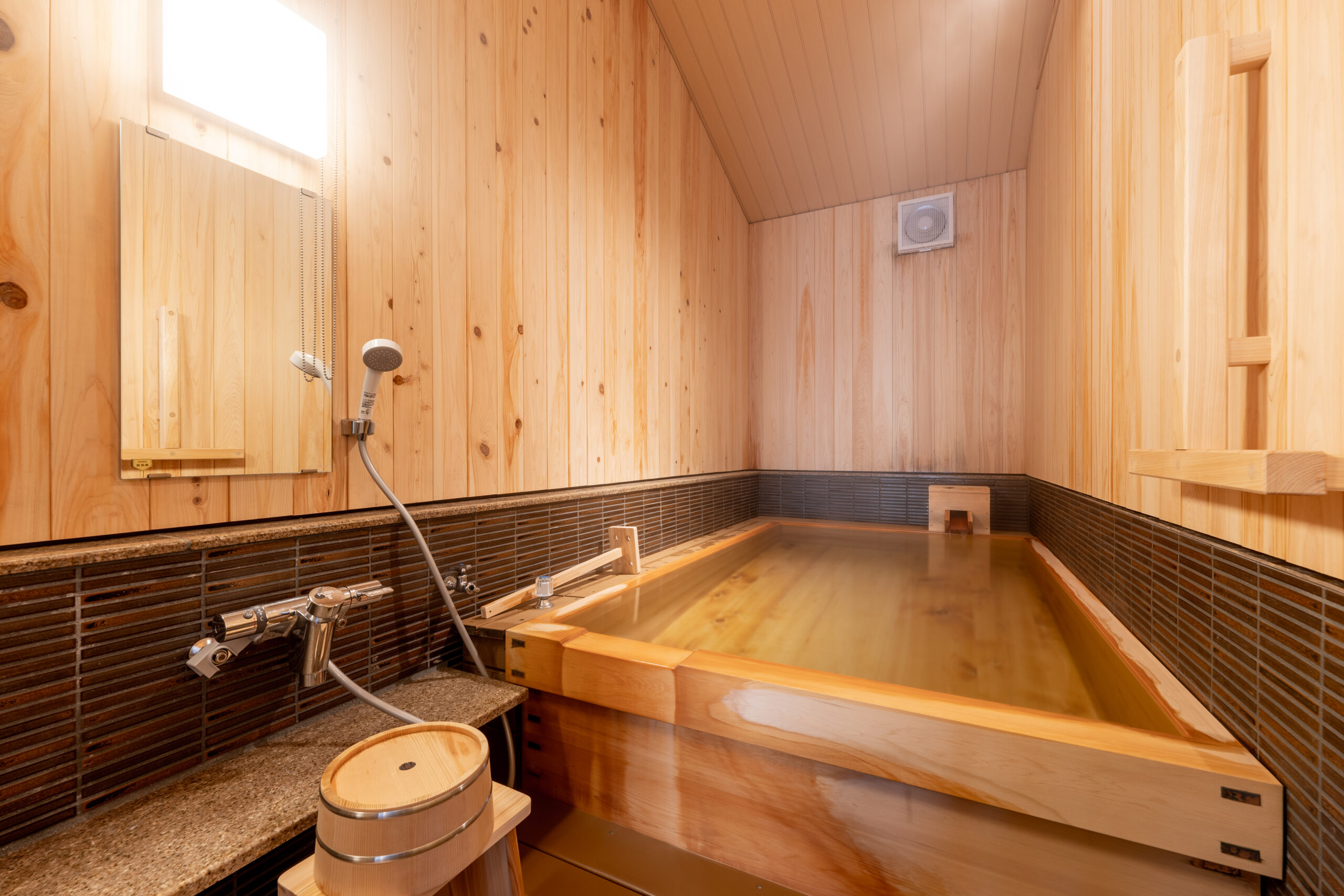 Private cypress-wood bath with hinoki tub and tiled wall in a warm timber bathroom
