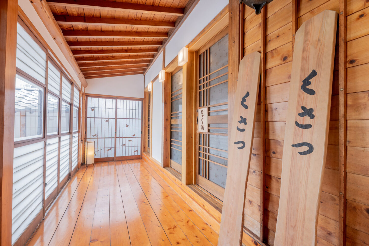 Sunlit wooden interior corridor with shoji windows and carved cedar plaques