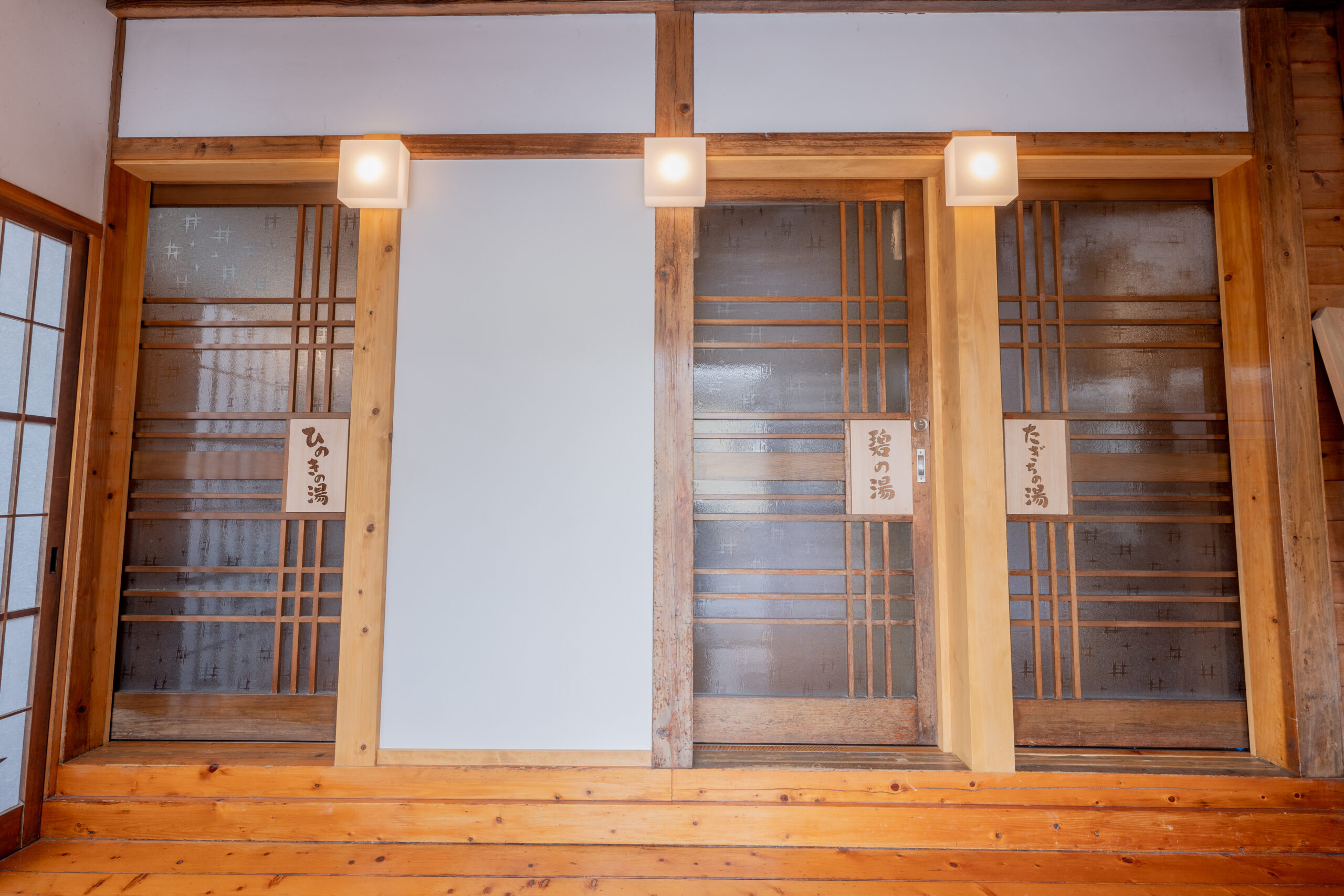 Row of private bath entrances with paper-screen doors and small wooden name plaques