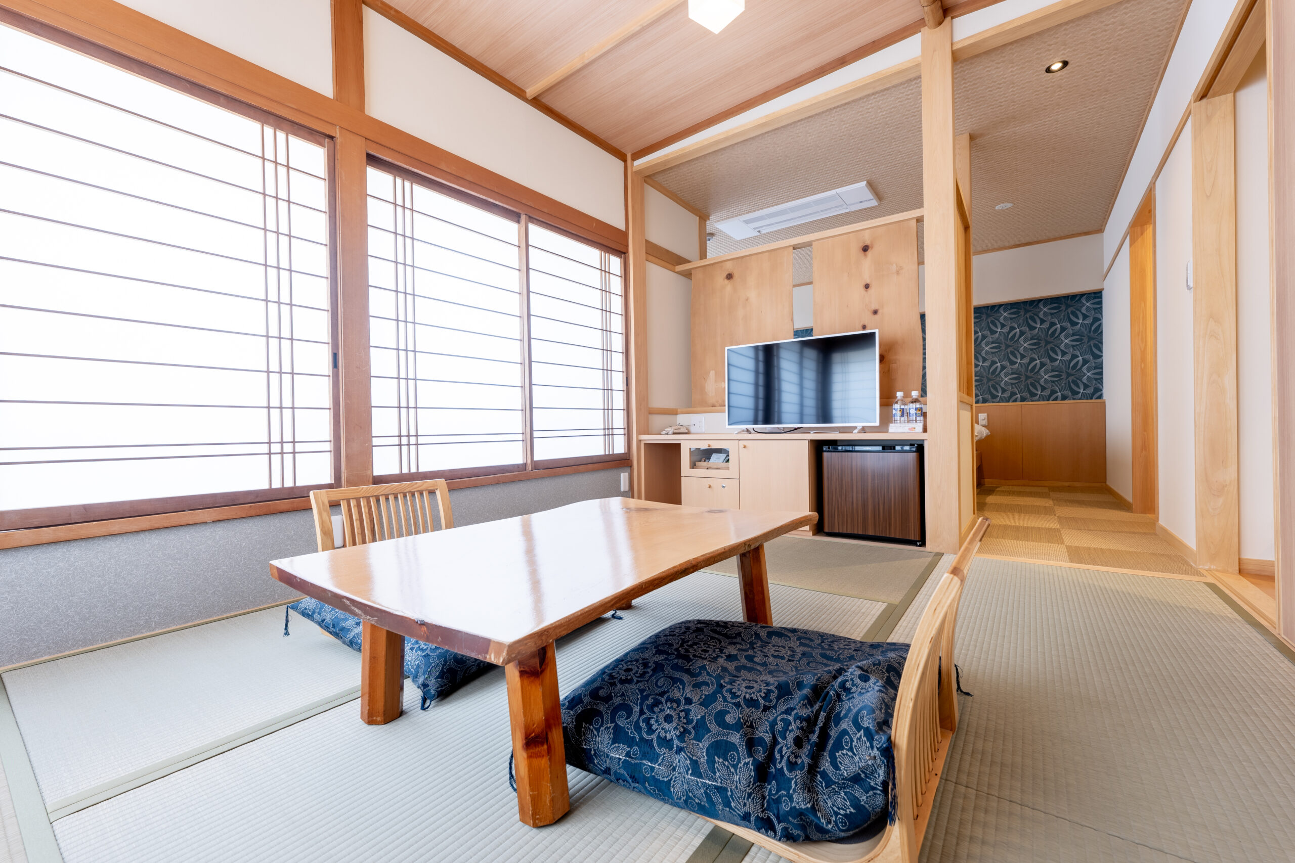 Modern tatami room with low table, floor seating, TV cabinet and tatami-floor corridor