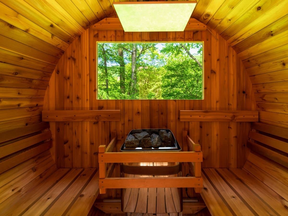 Cedar barrel sauna with forest-view window and lava stones at Zenshichinoyu Ohira, Zao Onsen