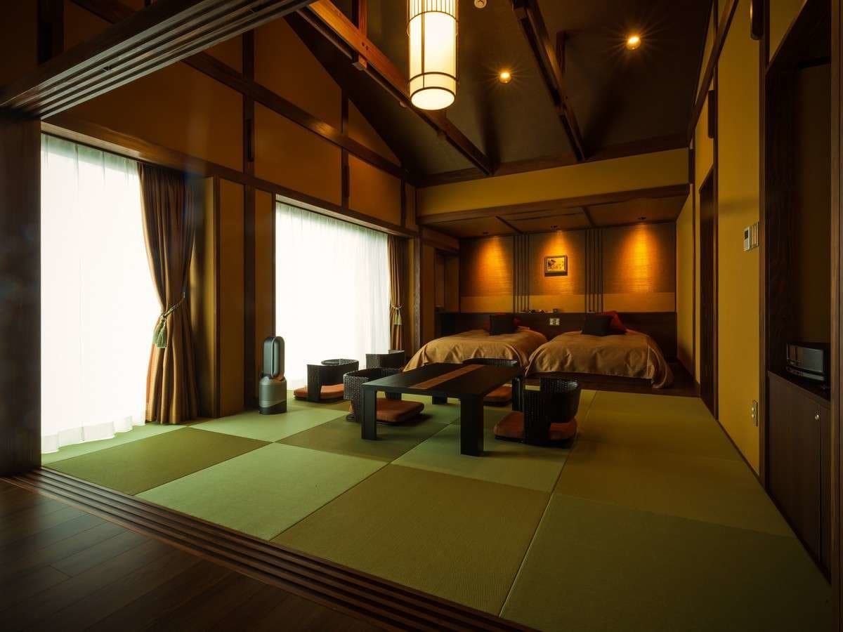 Tatami guest room with twin beds, low table and vaulted wooden ceiling at Zenshichinoyu Ohira, Zao Onsen
