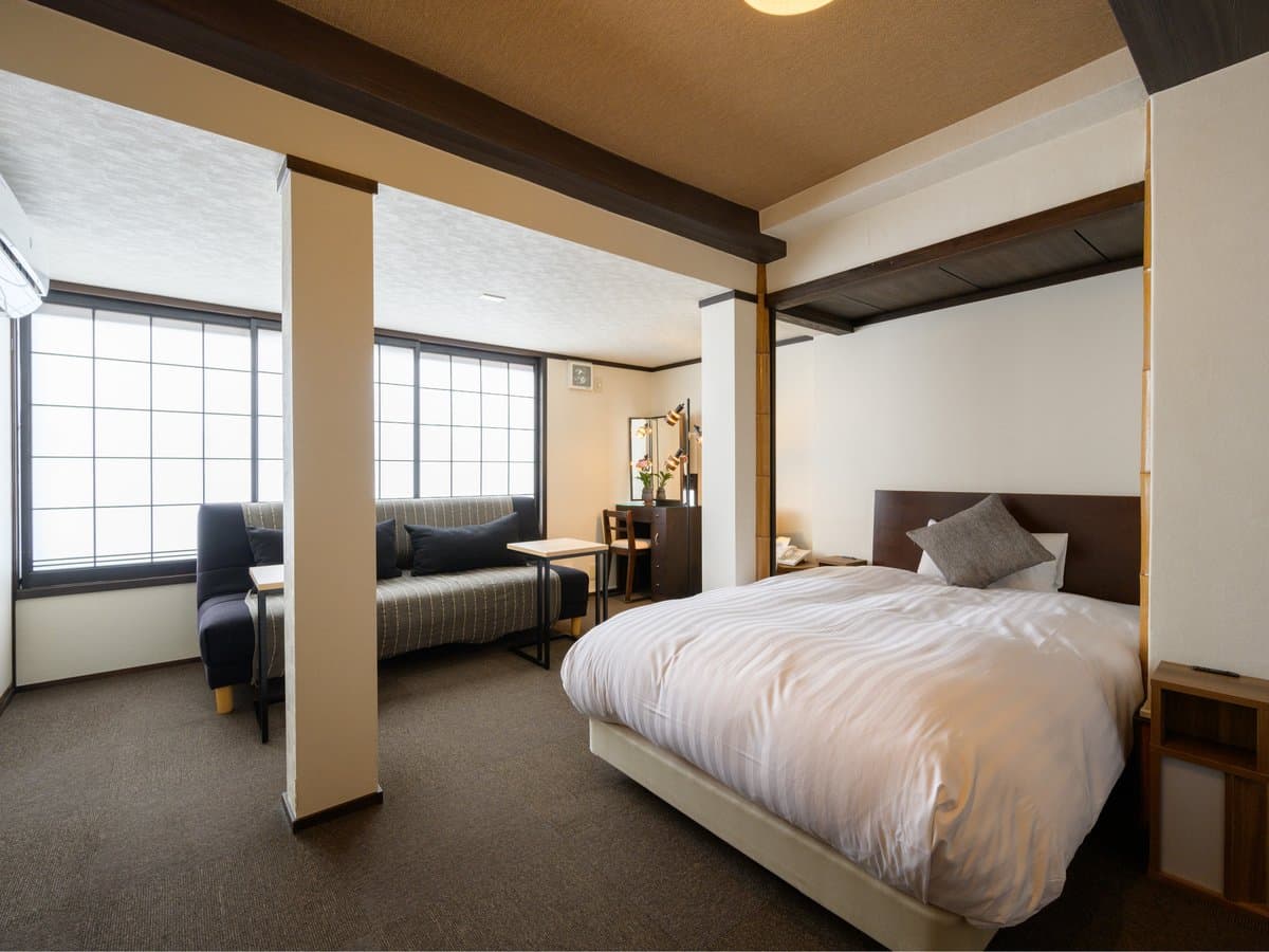 Wood-accented guest room with double bed, striped sofa and bright shoji windows, Koyado En, Kinosaki Onsen