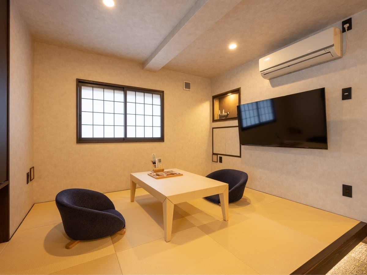 Tatami guest room with low table and modern blue lounge chairs beside a shoji window, Koyado En, Kinosaki Onsen