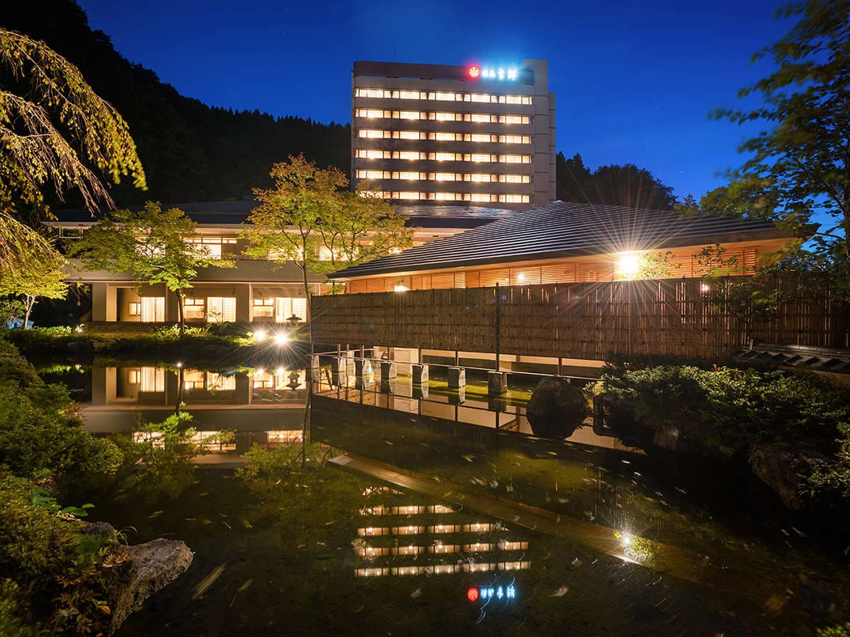 Illuminated main building mirrored in the garden pond on a clear blue evening, Yumoto Kissho, Naruko Onsen