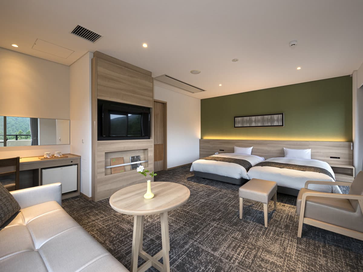 Modern Western-style twin guest room at Seiunso with a green accent wall, sofa and writing desk
