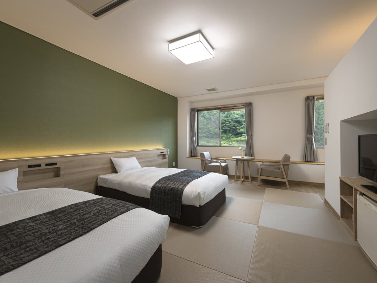 Japanese-Western twin room at Seiunso with tatami flooring, two beds and a garden-view window