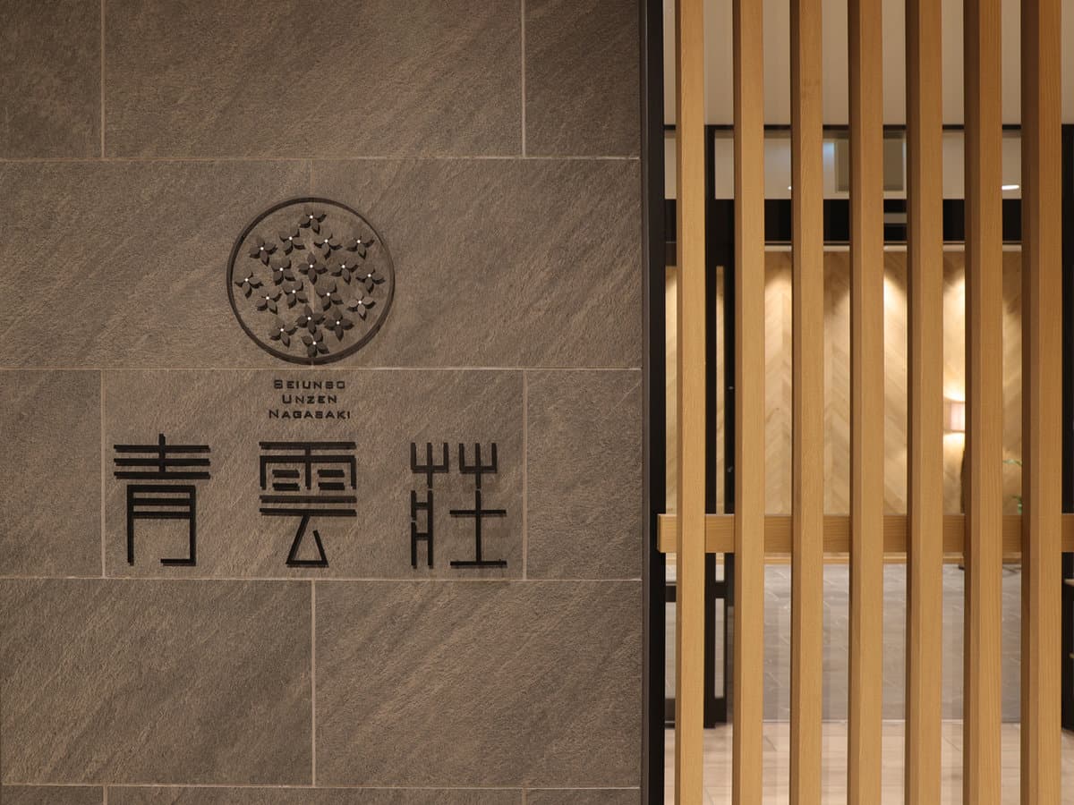 Stone entrance wall at Seiunso carved with the inn name beside wooden slat screening at the lobby