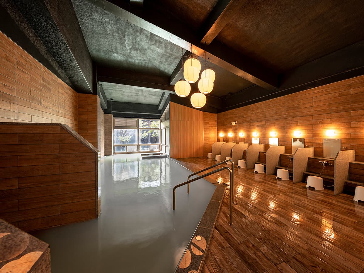 Indoor large bath at Seiunso with wooden walls, hanging lanterns and a stone-edged onsen pool