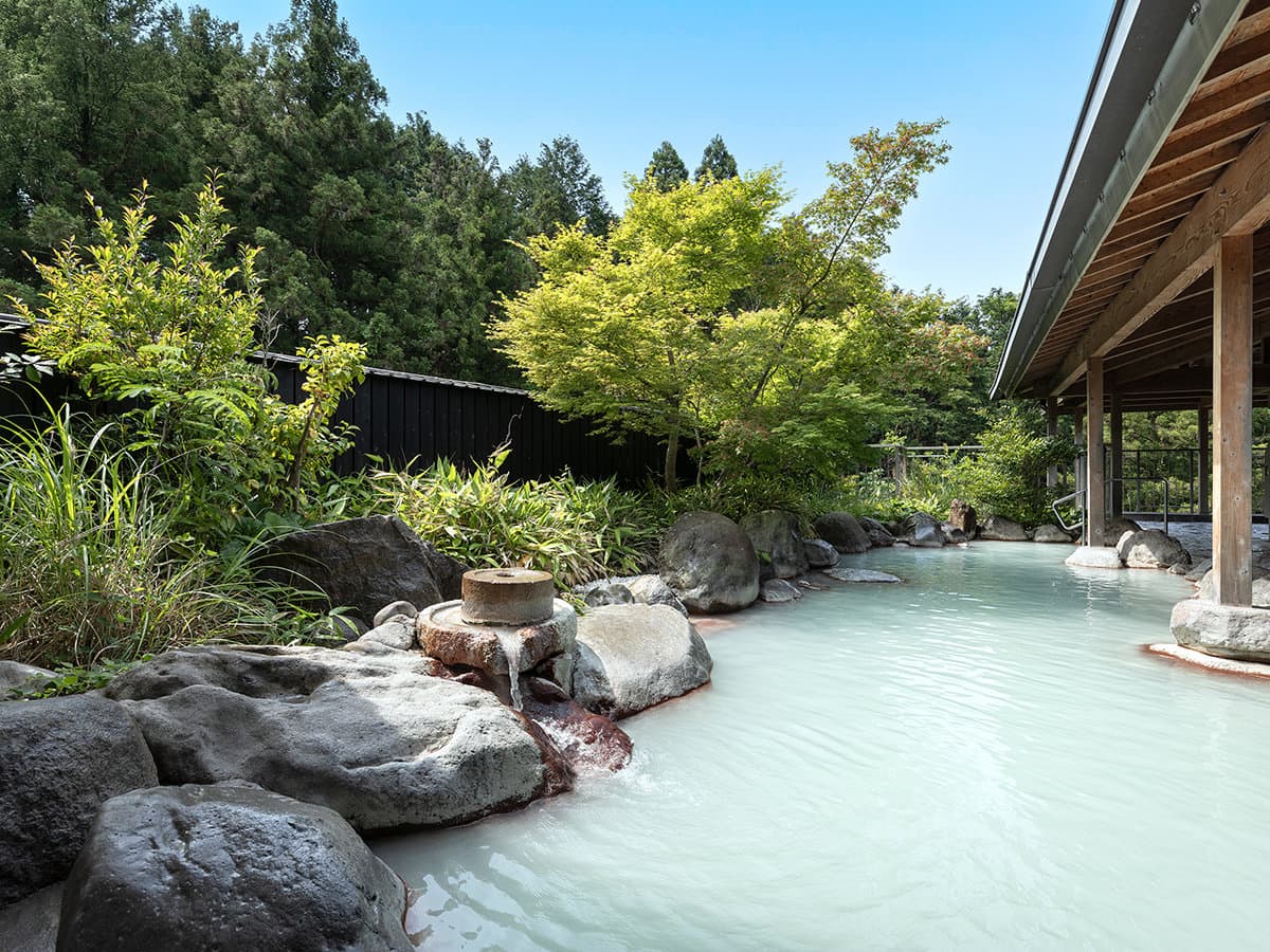 Outdoor rotenburo at Seiunso with milky-white Unzen onsen water surrounded by rocks and greenery