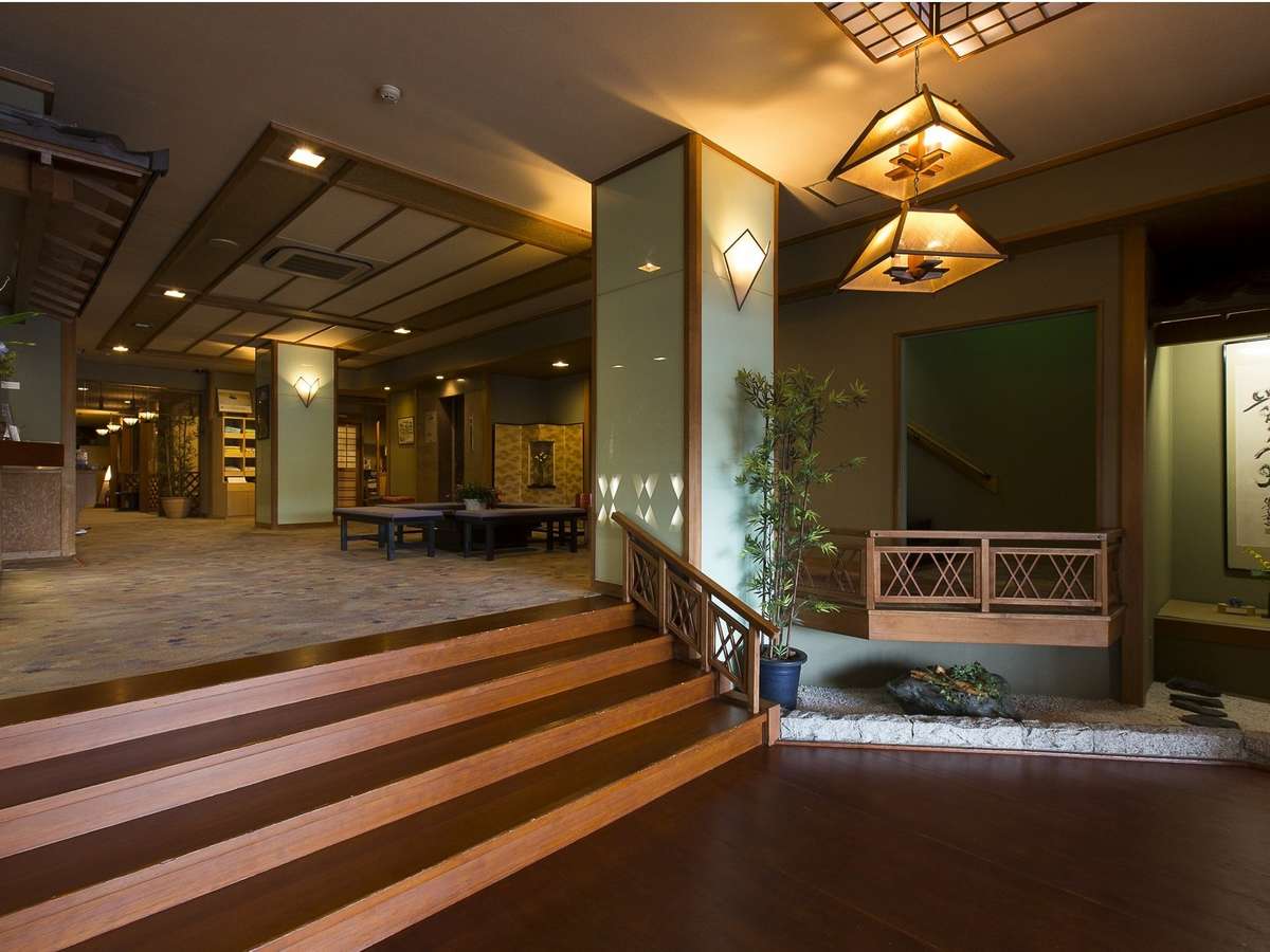 Warmly lit traditional lobby and lounge with wooden stairs and hanging lanterns at Ryokan Tachibana in Atami