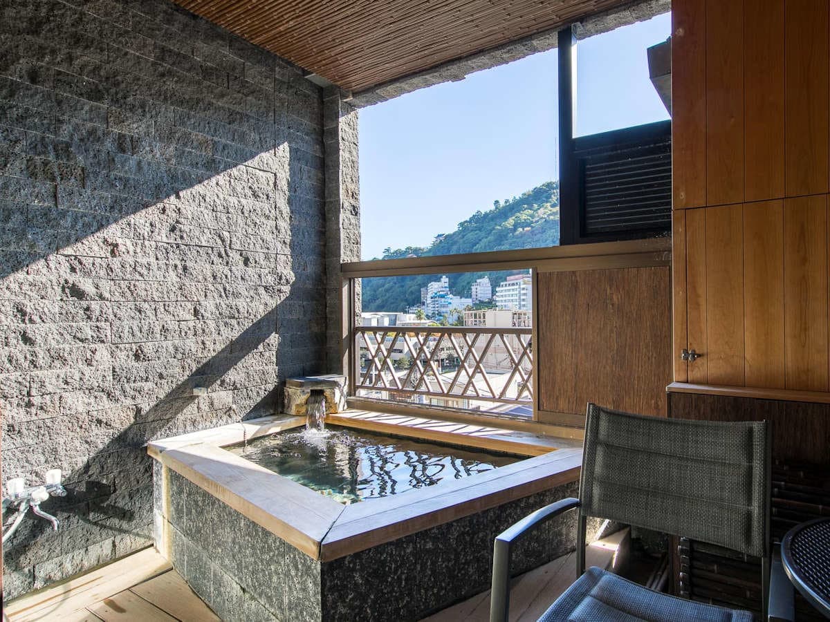 Private open-air hot spring bath on a guest-room terrace overlooking the Atami hillside