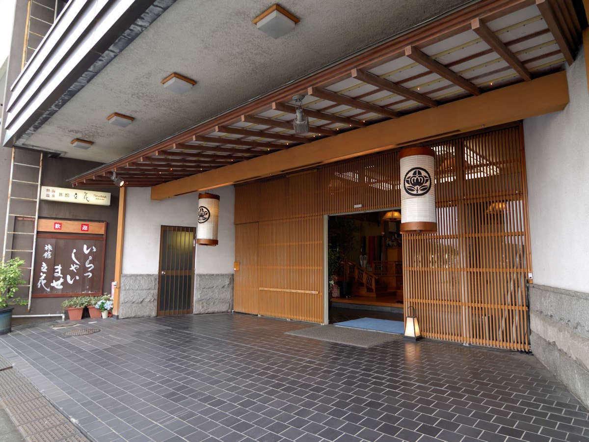 Entrance of Ryokan Tachibana in Atami Onsen with a wood-latticed canopy and lit lanterns