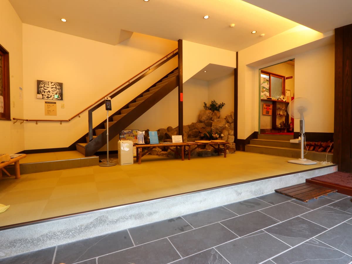 Kamiobo entrance lobby with a slate stone floor, raised tatami platform, wooden staircase and a small rock garden