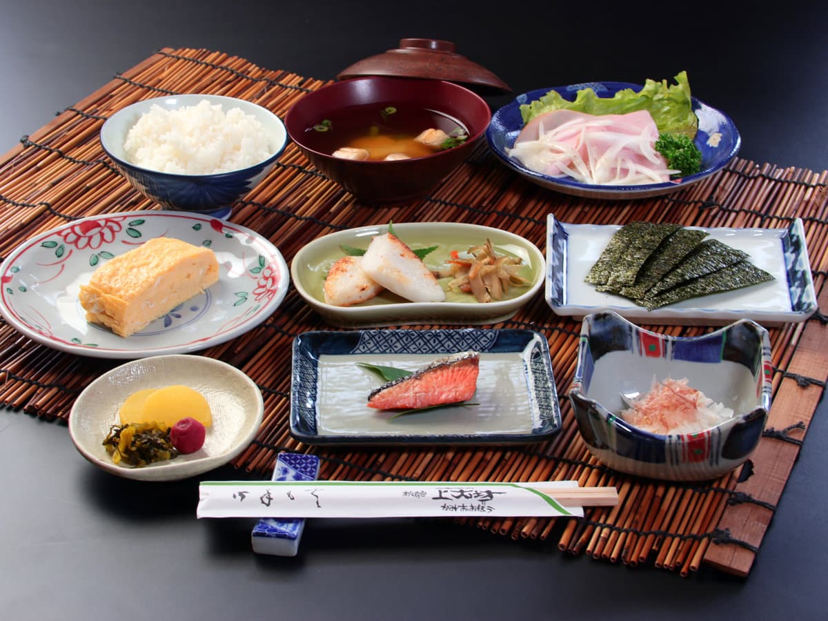 Japanese breakfast set at Kamiobo on a bamboo mat with rice, miso soup, grilled salmon, tamagoyaki, nori, pickles and small side dishes