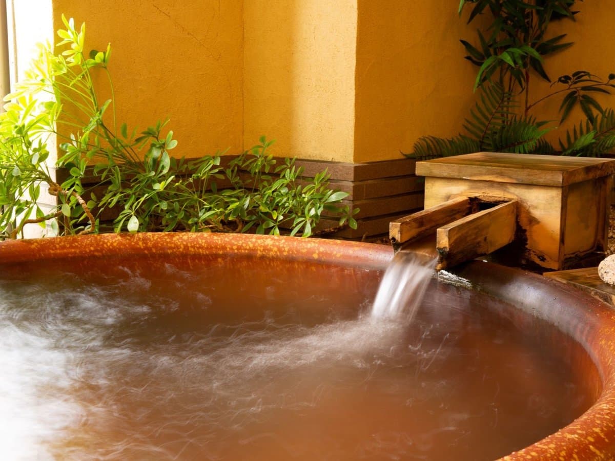 Round wooden private onsen bath at Oyado Seri surrounded by greenery