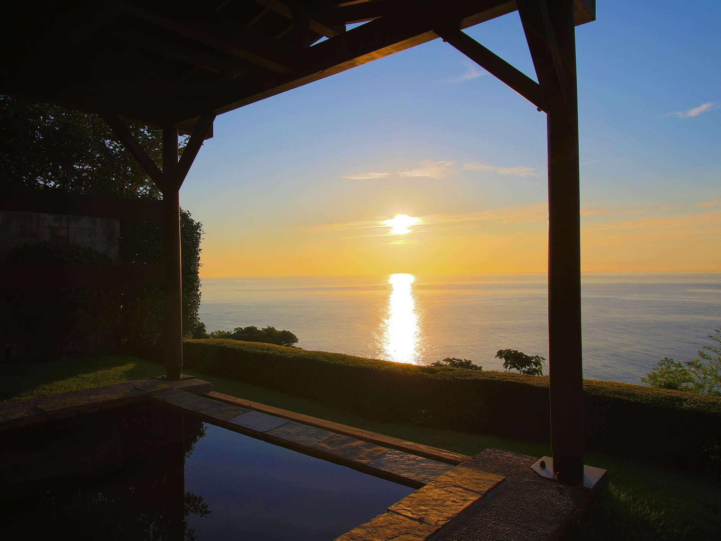 Private open-air rotenburo overlooking the ocean at sunset under a timber pavilion at Tsuki no Usagi, Izu-Kogen