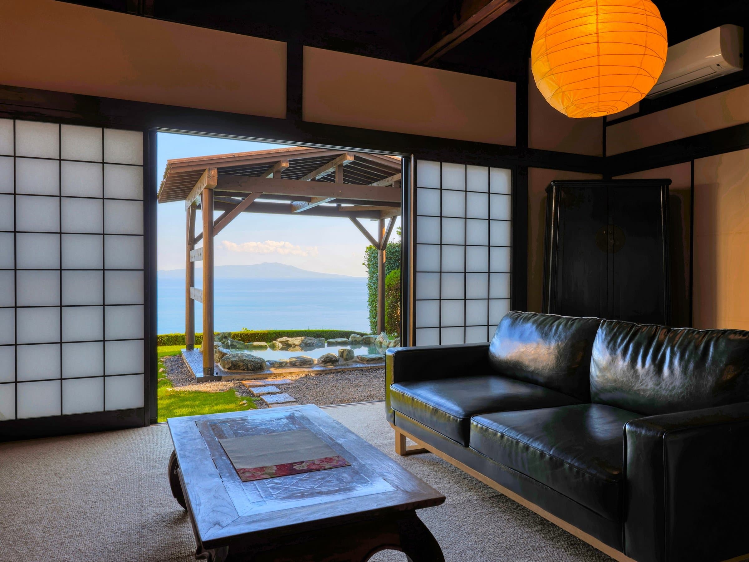 Guest room lounge with leather sofa opening onto a private open-air ocean-view bath at Tsuki no Usagi, Izu-Kogen