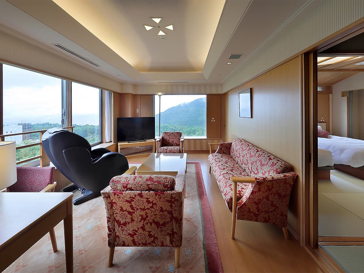 Bright suite living room with floral sofas, massage chair and mountain views through corner windows