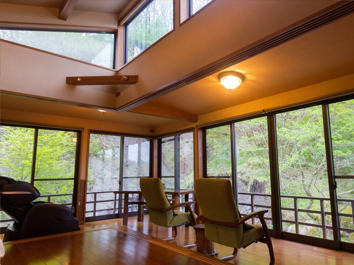 Premium tatami guest room at Hozantei with a panoramic window over the surrounding forest