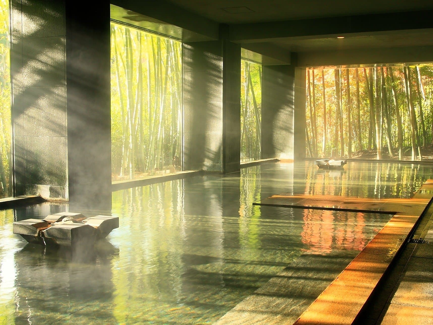 Yusai signature indoor bath with sunbeams streaming through floor-to-ceiling bamboo-grove windows